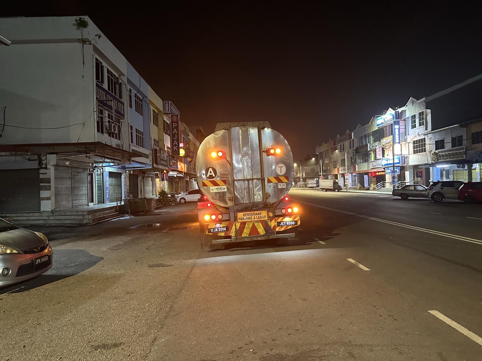JB night street — tank truck passing through sleeping shophouses