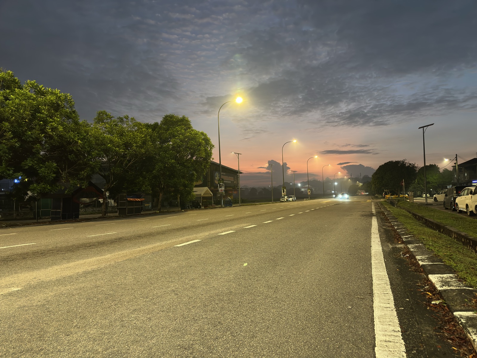 Dawn over Johor Bahru highway — pink sky, street lights, empty road stretching west