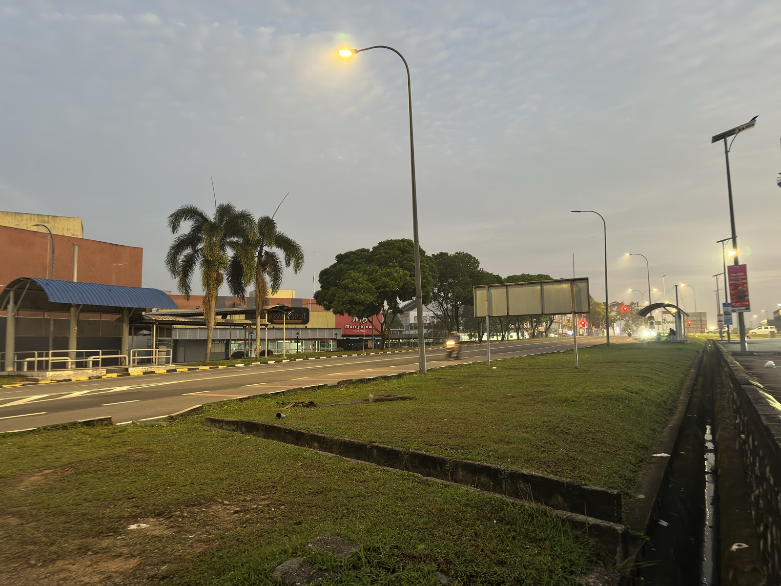 KIP Mall area at dawn — pink sky, palm trees, empty parking lot, Johor Bahru