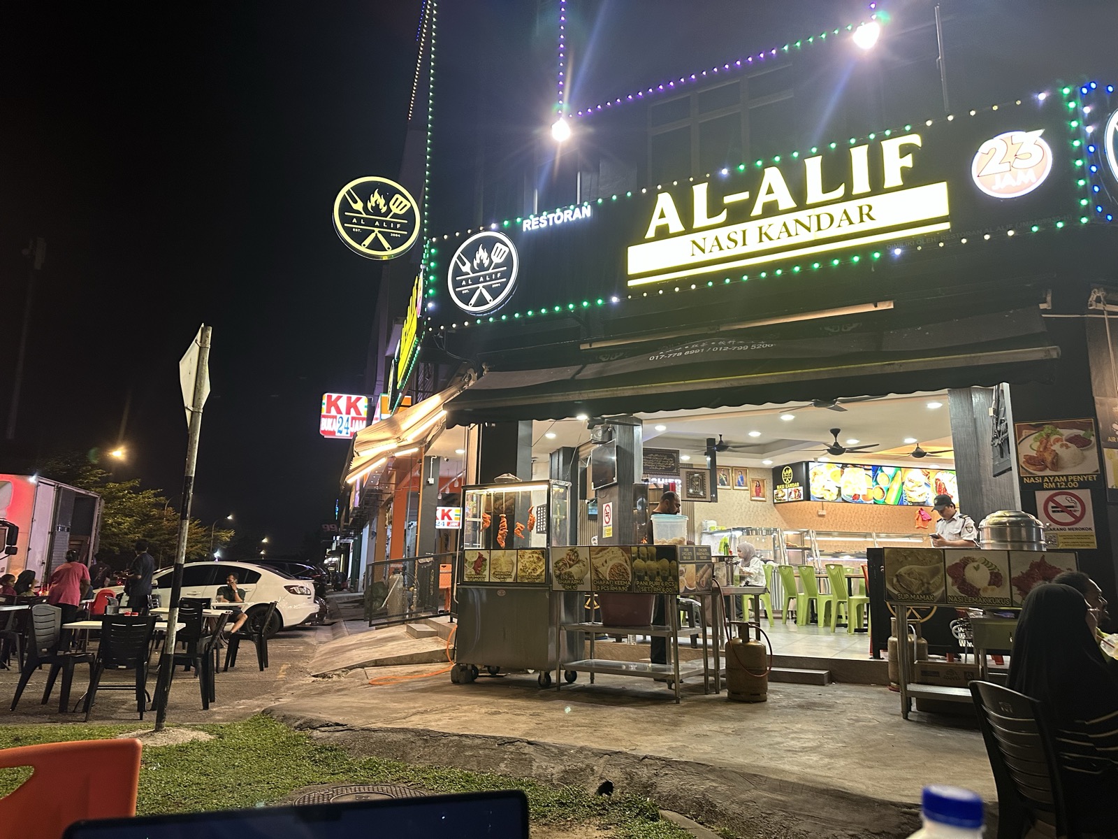 Al-Alif Nasi Kandar restaurant front — neon signs, open-air seating, JB at night