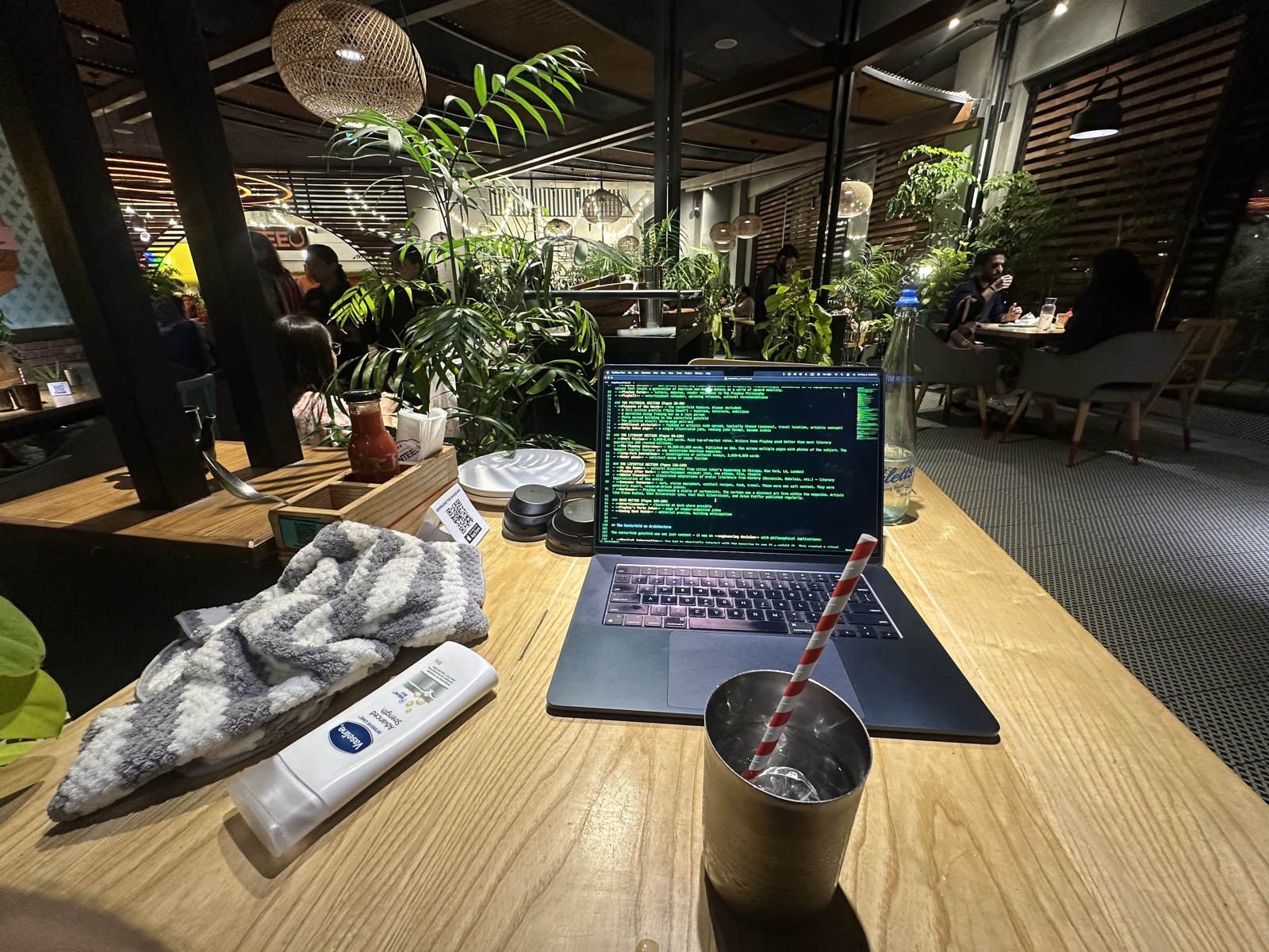 MacBook open in a restaurant with a tropical plant wall