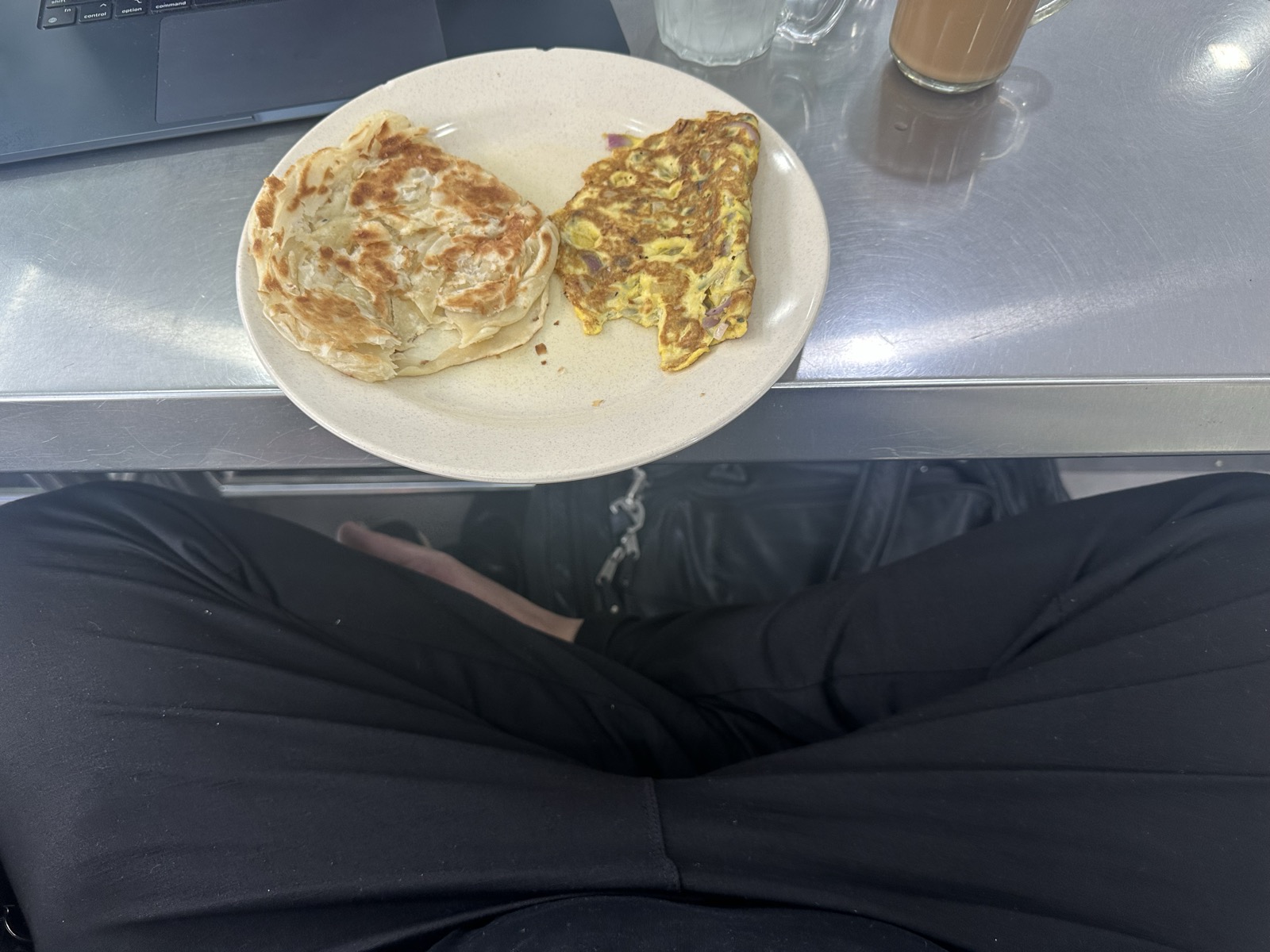POV: roti canai plate and crossed legs