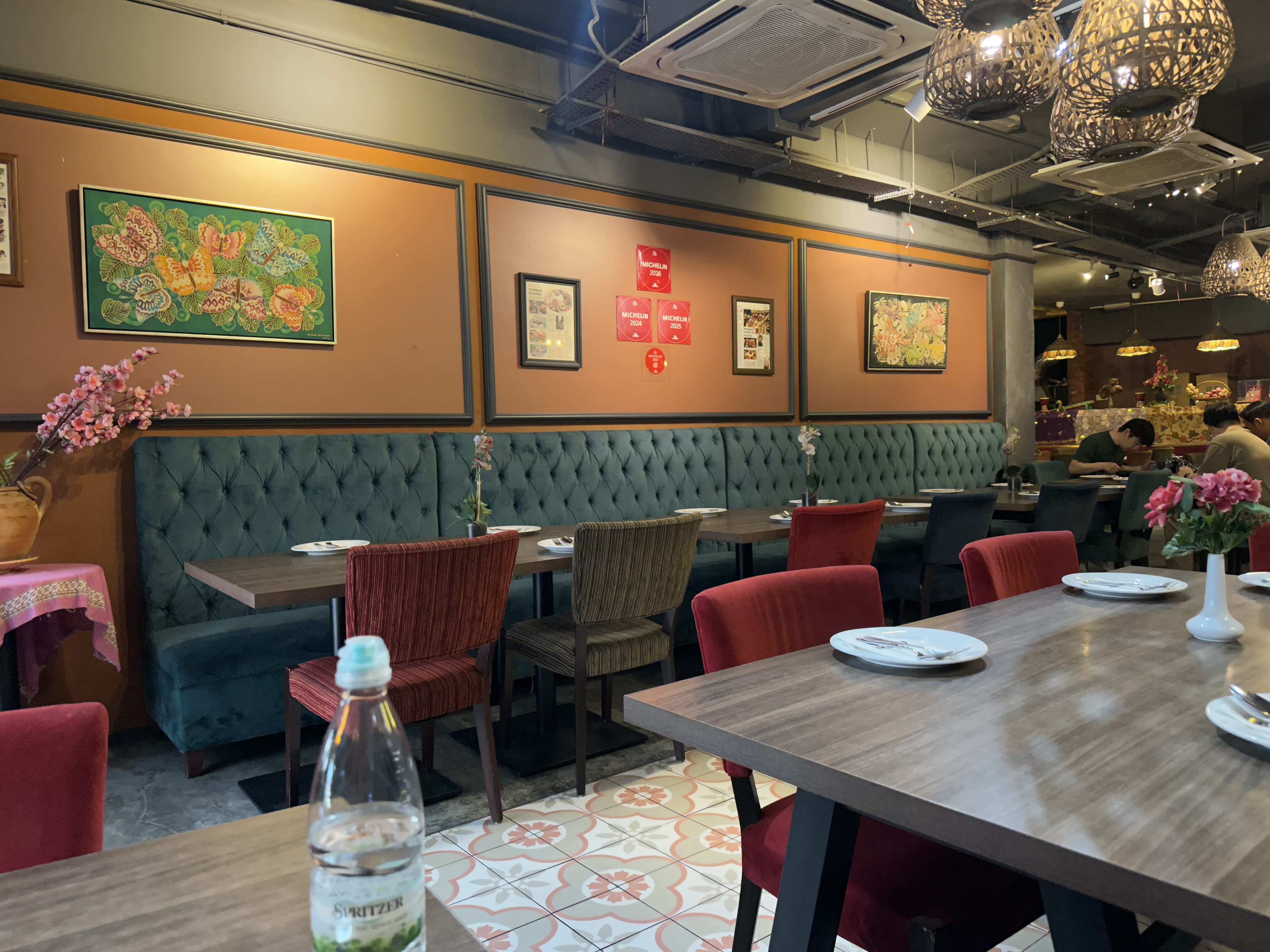 Restaurant interior — green velvet banquettes, chandeliers, Malaysian art