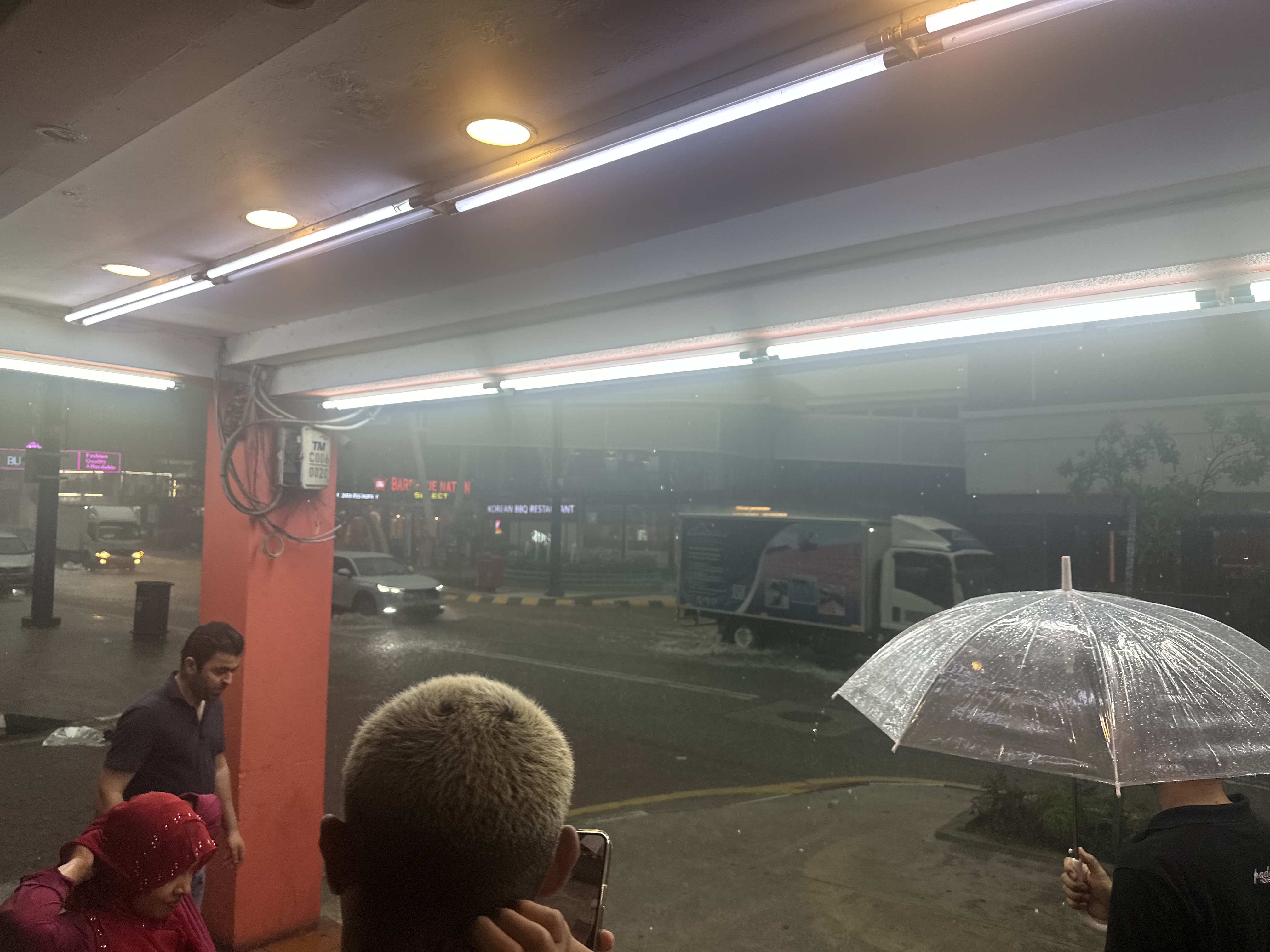 Heavy rain in KL — people with umbrellas, foggy streets