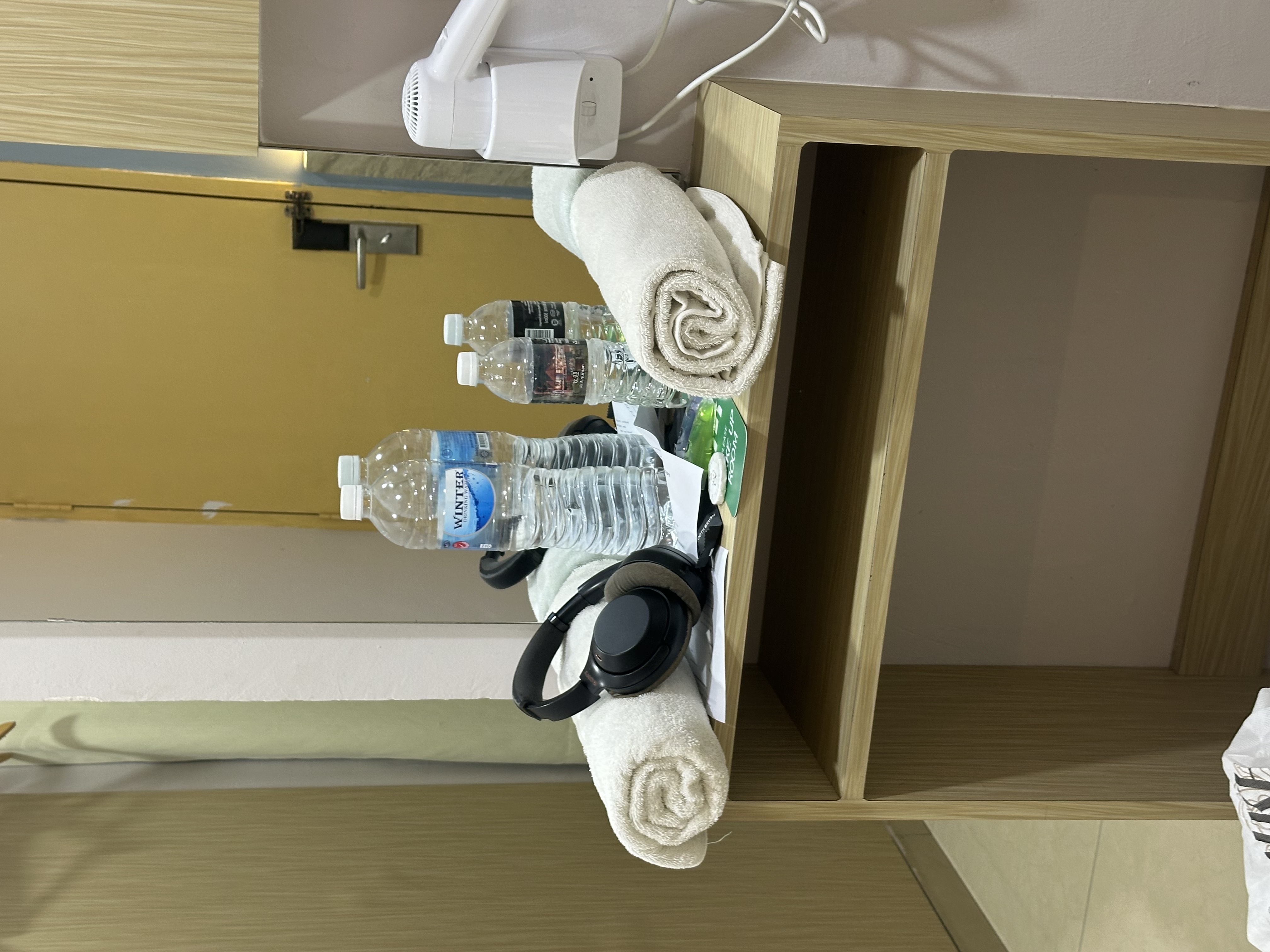 Hotel room — water bottles, headphones, towel on nightstand