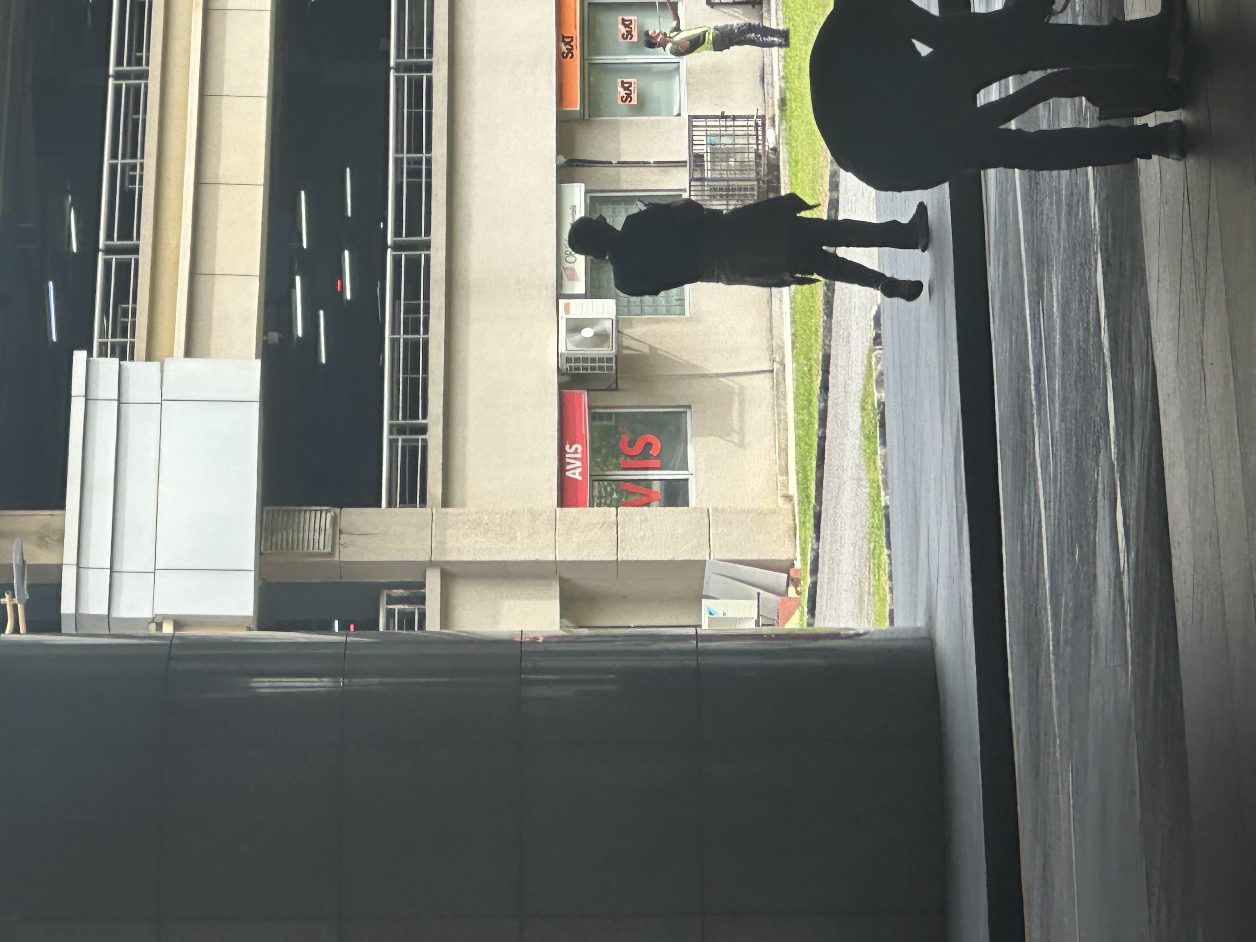 Haadi silhouetted at KLIA2 with Avis sign