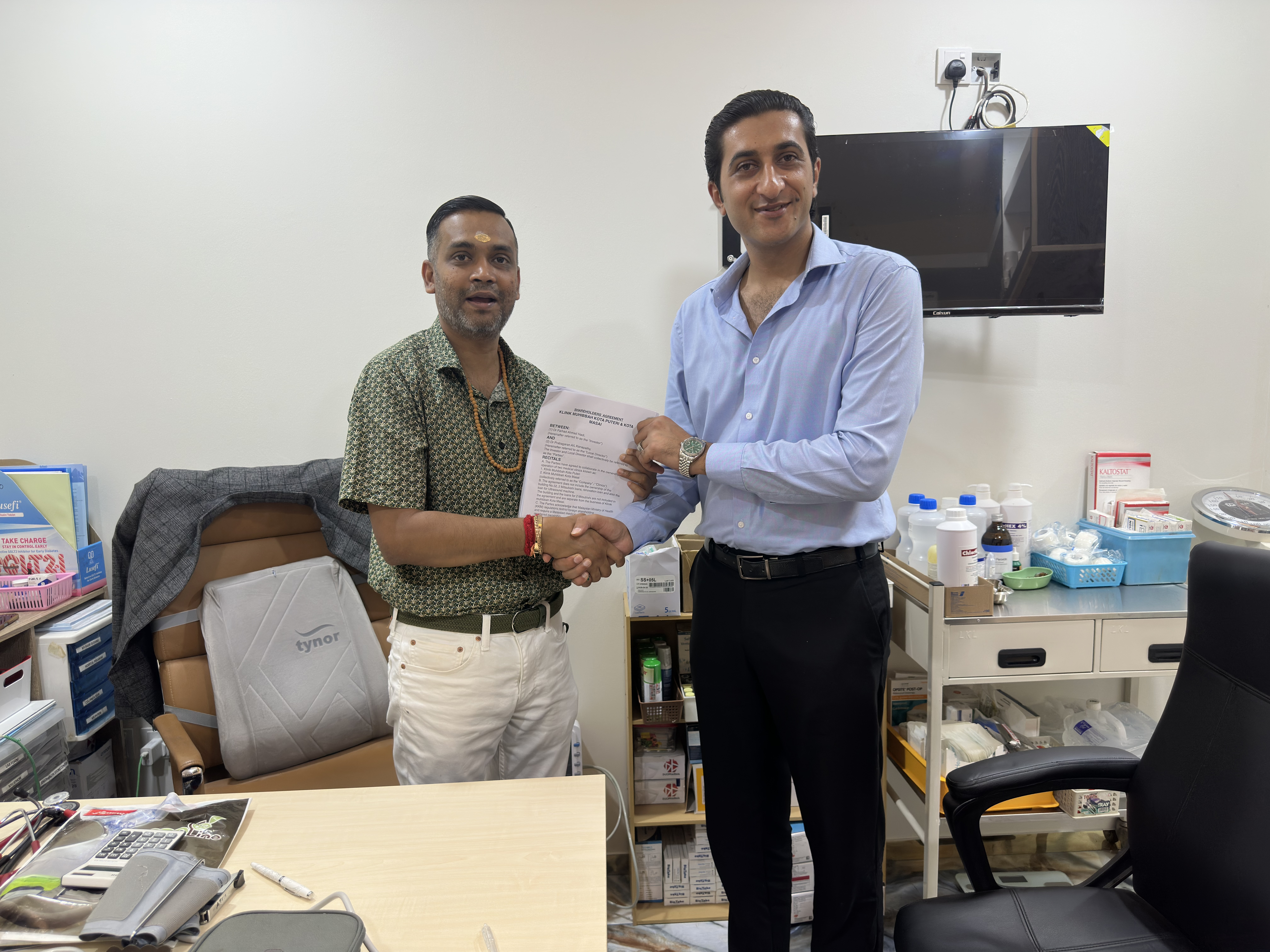 Dr. Prabagaran and Haadi shaking hands after signing MoVo-X contract at Klinik Muhibbah