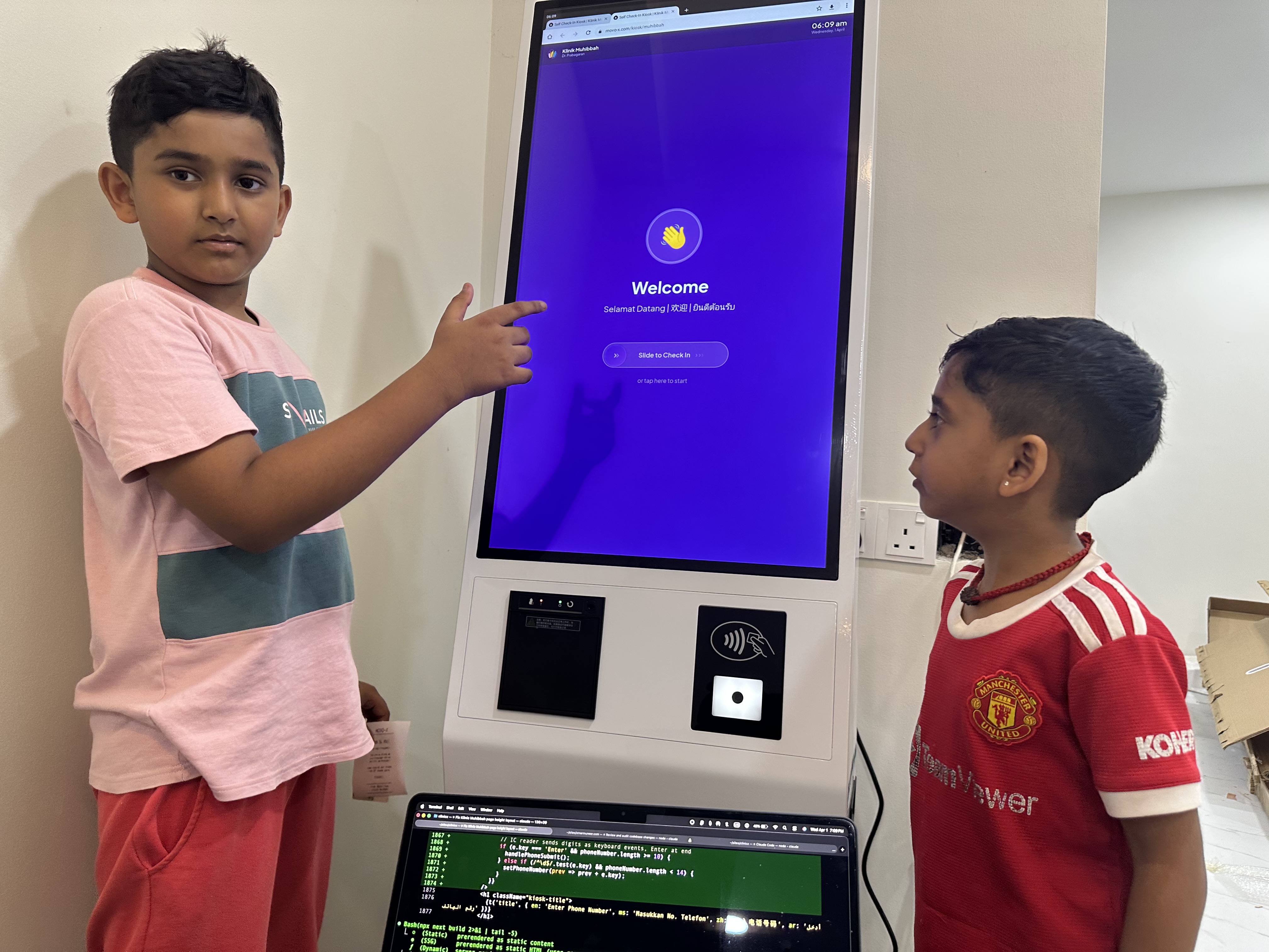 Two kids testing the MoVo-X kiosk — pointing at the Welcome screen