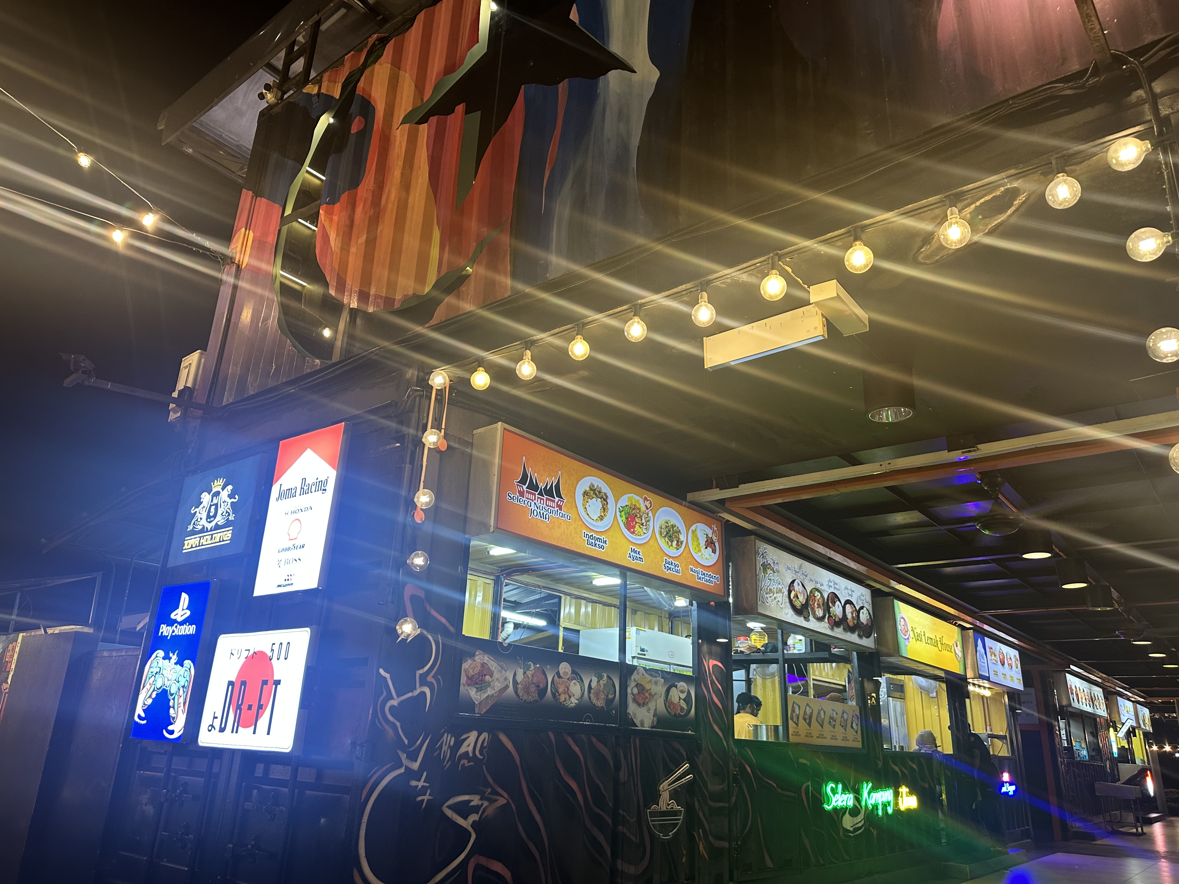 Inside The J — food stalls, PlayStation signs, neon glow