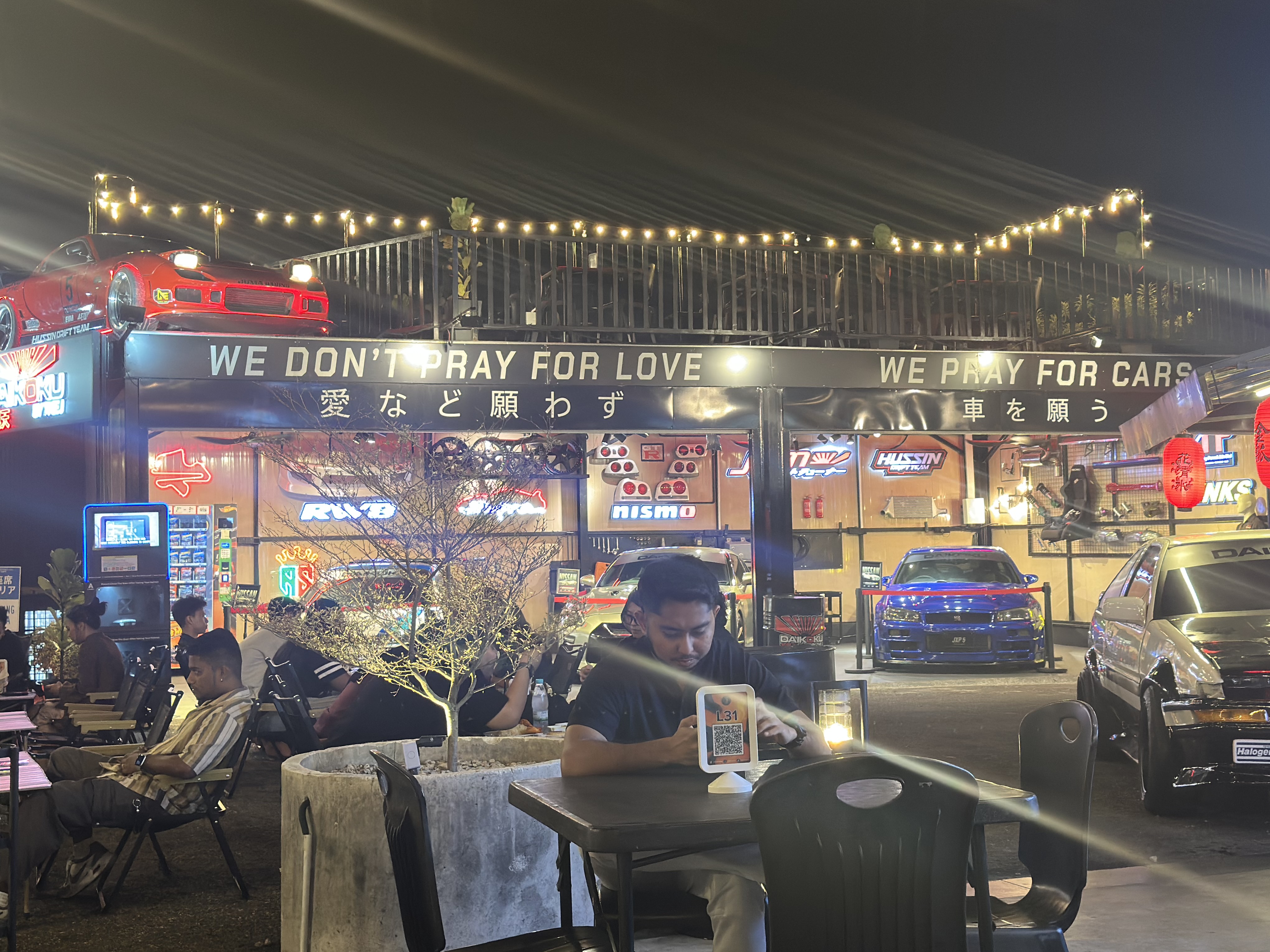 The J — diners under the WE DON'T PRAY FOR LOVE sign, blue Skyline