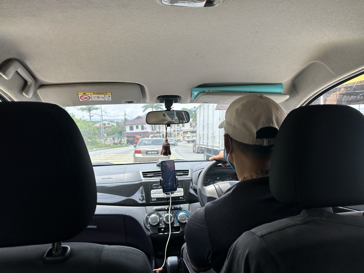 Inside a Grab ride — driver with cap, JB streets