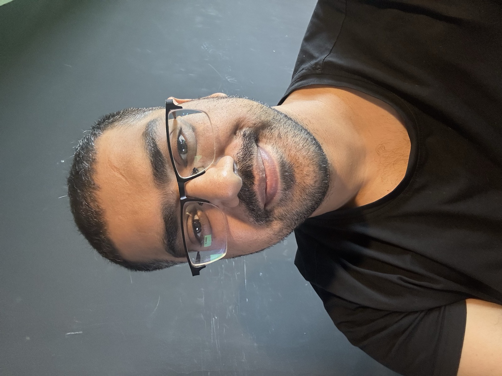 Omer selfie in black shirt, glasses reflecting green, tired but present